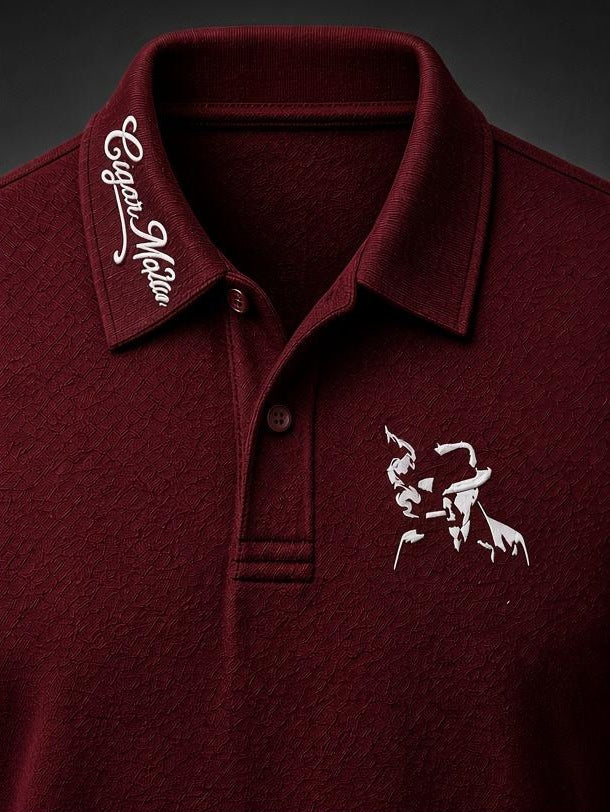 Maroon dri-fit polo, white script collar embroidery, white embroidered smoking-man-in-fedora silhouette on the chest
